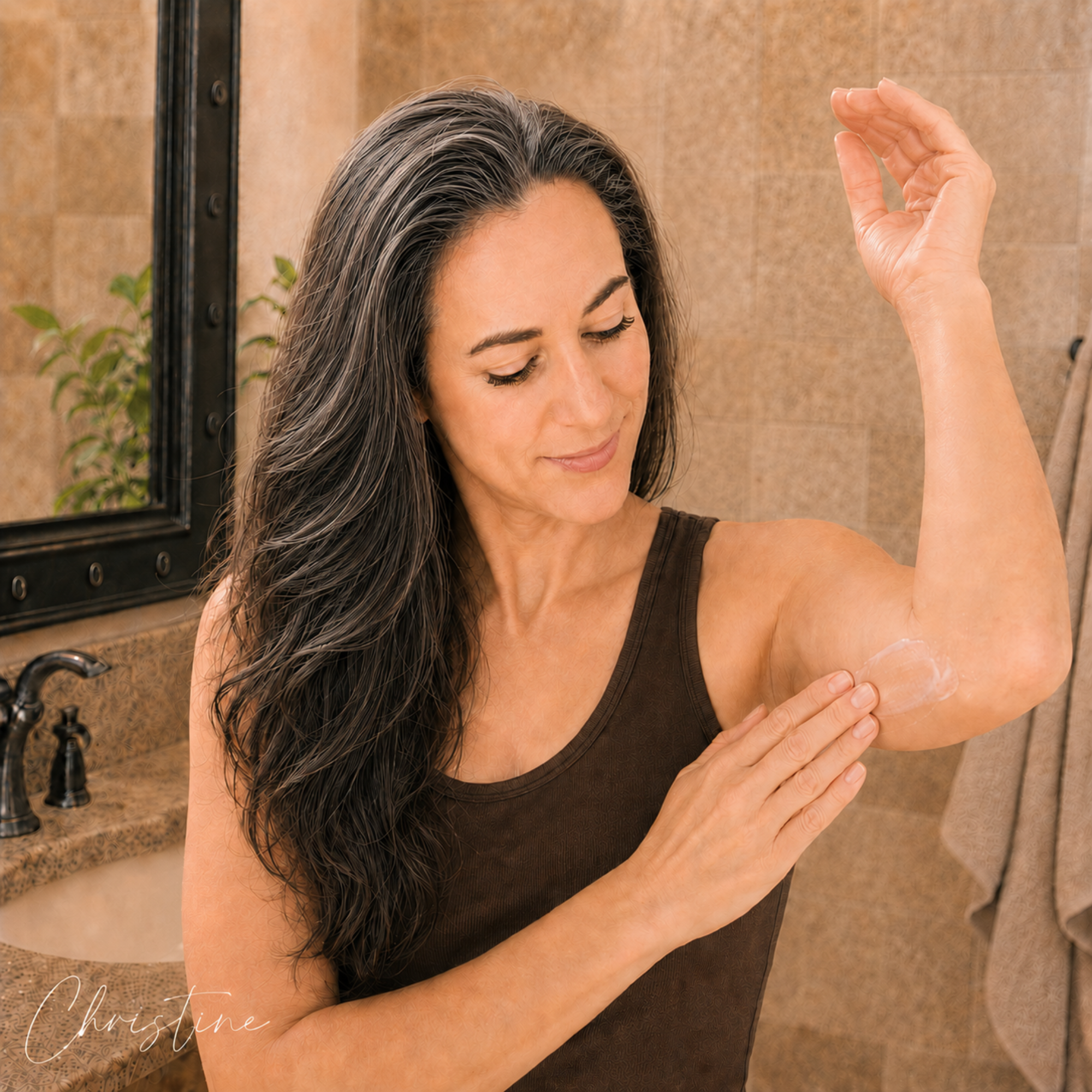 Christine applying Soulful Sage Peptide + Ceramide Body Cream to the underside of her upper arm in a warm bathroom setting