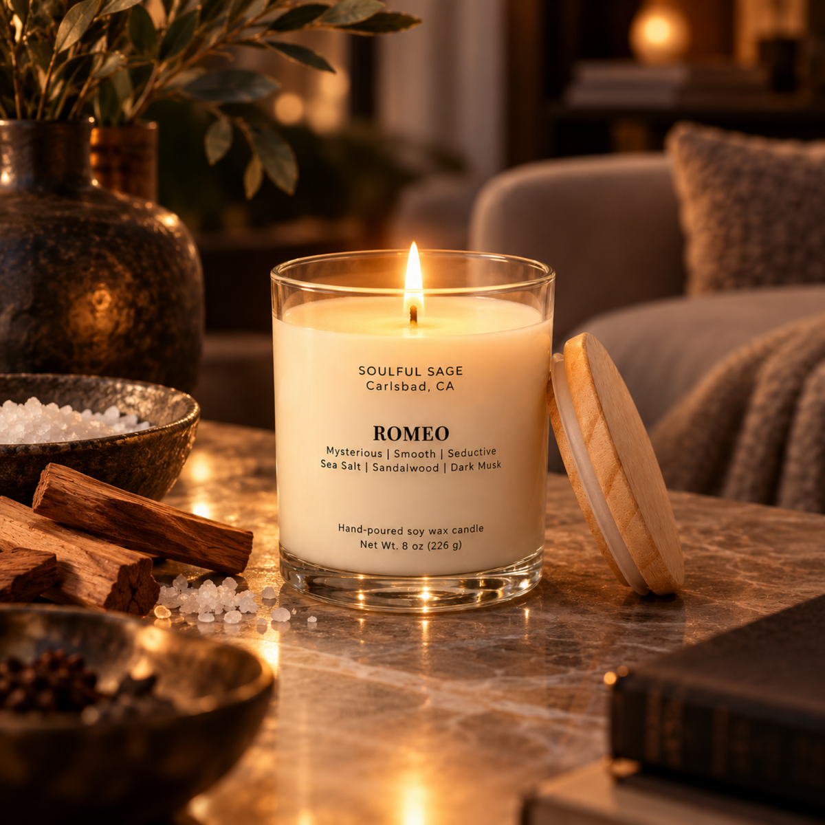 Romeo soy candle glowing in a warm, intimate room with dark wood, soft neutral textiles, and moody ambient light.