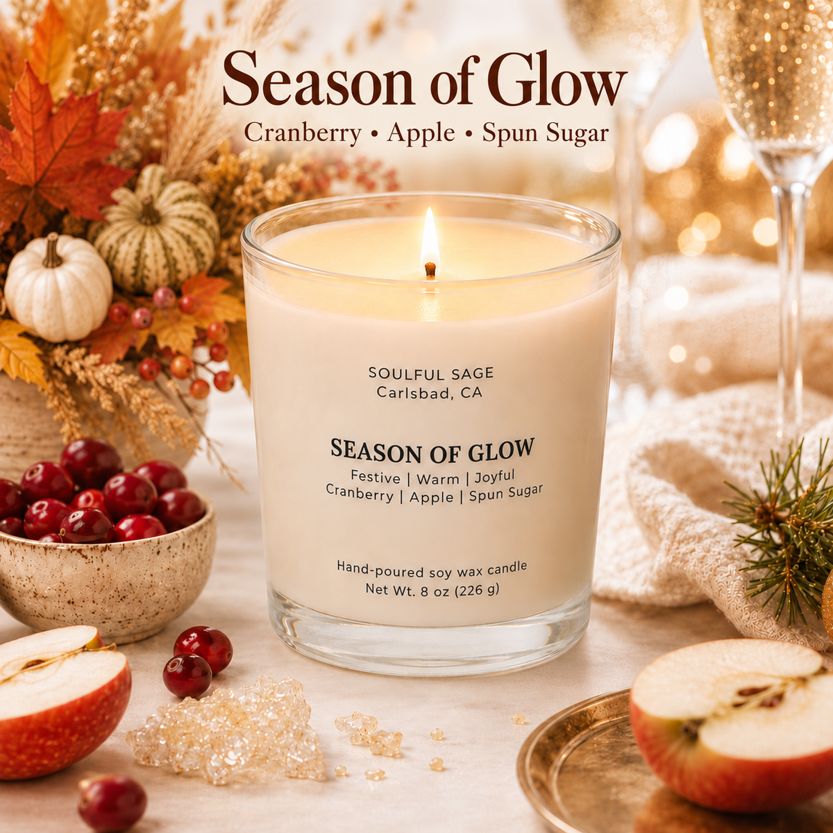 Season of Glow soy candle by Soulful Sage styled with cranberry, apple, spun sugar, evergreen, fall florals, champagne glasses, and warm festive candlelight.